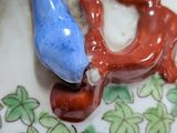 a blue bird sitting on top of a plate with a red bird on it