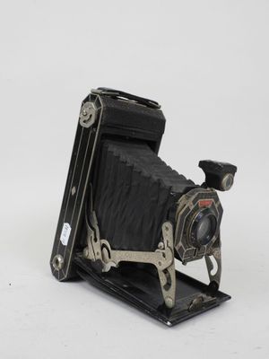 an old black camera sitting on top of a white surface