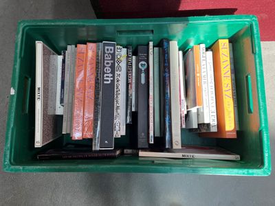 many books in a green box on the floor