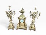 trois bougeoirs en argent et une horloge sur fond blanc