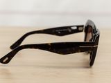 sunglasses on a wooden table with a white wall in the background