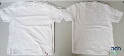 two white t - shirts sitting on top of a table next to each other