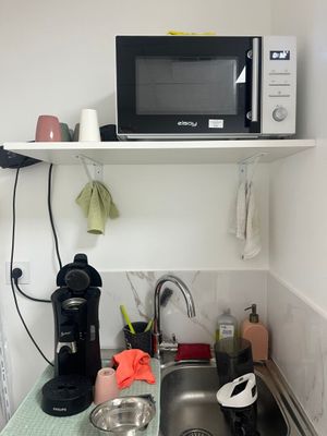 a microwave on a shelf above a sink in a kitchen