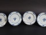 four blue and white plates with flowers on them on a black surface