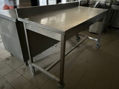 table de travail en acier inoxydable dans une cuisine professionnelle, avec une personne à l'arrière-plan