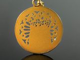 an image of a gold pendant with a tree of life design on it