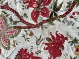 a red and green floral pattern on a white table cloth