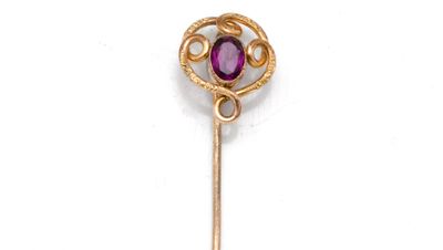 un gros plan d'une épingle plaquée or ornée d'une pierre violette