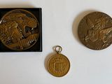 deux médailles d'or et une médaille d'argent posées sur une surface blanche