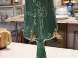 a green bell sitting on top of a table in a room