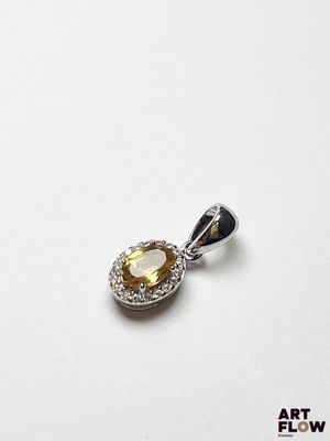 un gros plan d'un pendentif en diamants jaunes et blancs posé sur une surface blanche