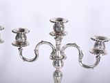 three silver candelabs with flowers on each of them on a table