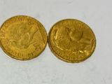 two gold coins sitting side by side on a white surface