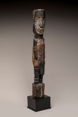 une statue en bois représentant un homme debout sur un socle noir