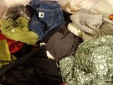 a pile of clothes sitting on a bed next to a pillow