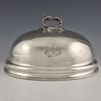 un plat ancien en argent recouvert d'un couvercle en métal orné d'un blason sur le dessus