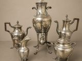 trois théières en argent et une cafetière sur une table