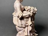 statue of a woman sitting on a stool holding a bouquet of flowers