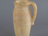 un vase muni d'une anse, avec deux figurines à côté