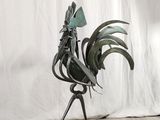 a metal rooster sculpture on a wooden floor