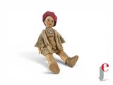 a small doll sitting on the ground with a red hat