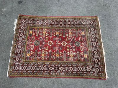 a red rug with a floral design on a grey floor
