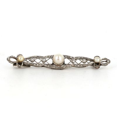 un gros plan sur une broche ornée de perles et de diamants