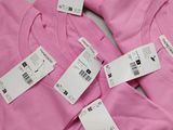 pink t - shirts with price tags on them sitting on a table