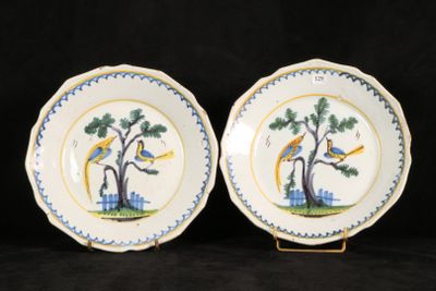 two blue and white plates with birds on them sitting on a black surface