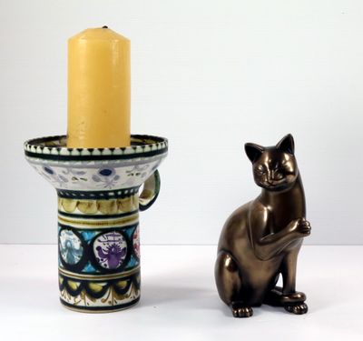 une statue de chat à côté d'un bougeoir avec une bougie