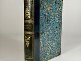 a blue book with gold trim sitting on top of a white table