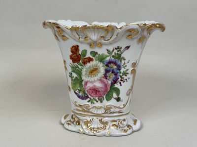 un vase blanc avec des fleurs sur une table