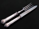 un service d'argenterie composé d'un couteau et d'une fourchette, posé sur un fond noir