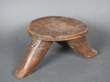 un vieux tabouret en bois posé sur une surface grise