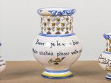 trois vases posés sur une table, sur lesquels figurent des inscriptions