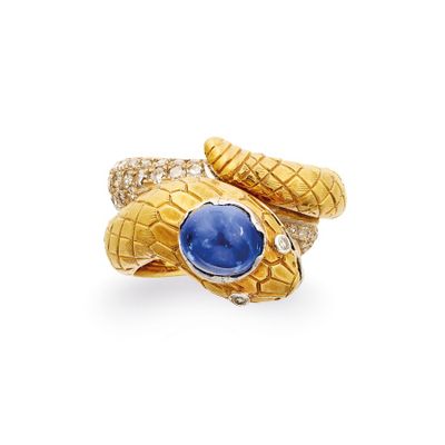 un gros plan d'une bague en or en forme de serpent sertie d'une pierre bleue