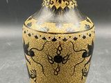 un vase doré orné de motifs noirs et blancs