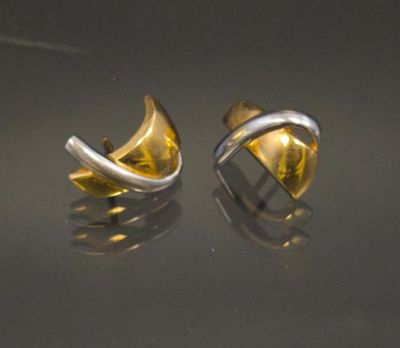 a pair of gold and silver earrings on a black surface