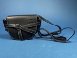 a black purse with a strap on it sitting on a blue surface