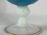 a blue glass with gold designs on it on a white surface