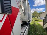 a white truck with a red stripe parked next to a house