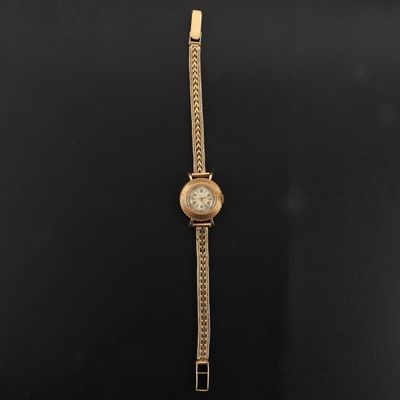 une montre en or posée sur une surface noire, entourée d'une chaîne
