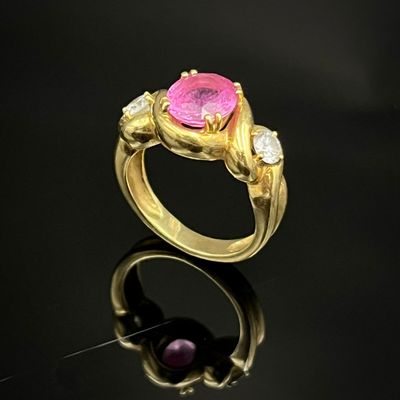 un gros plan d'une bague ornée d'une pierre rose sur un fond noir