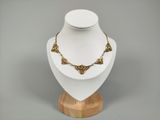 collier posé sur un support en bois, sur fond gris