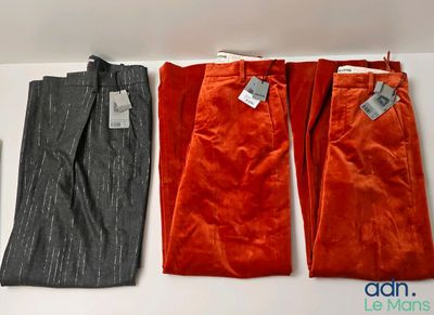 three pairs of pants are lined up on a shelf