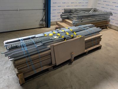 Plusieurs piles de barres d'acier sont empilées sur des palettes dans un entrepôt