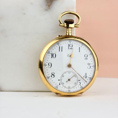 un gros plan d'une montre de poche en or posée sur une table en marbre
