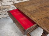 a wooden table with a red drawer underneath it