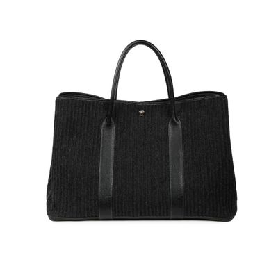a black tote bag sitting on top of a white surface