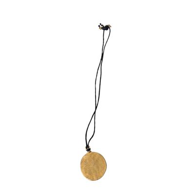a close up of a necklace with a gold disc on a black cord